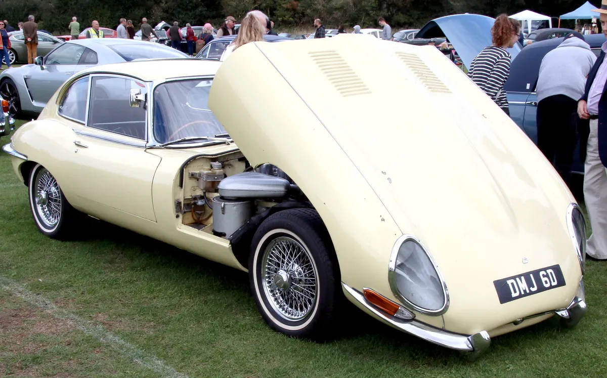 A classic British sports car with its hood raised for service